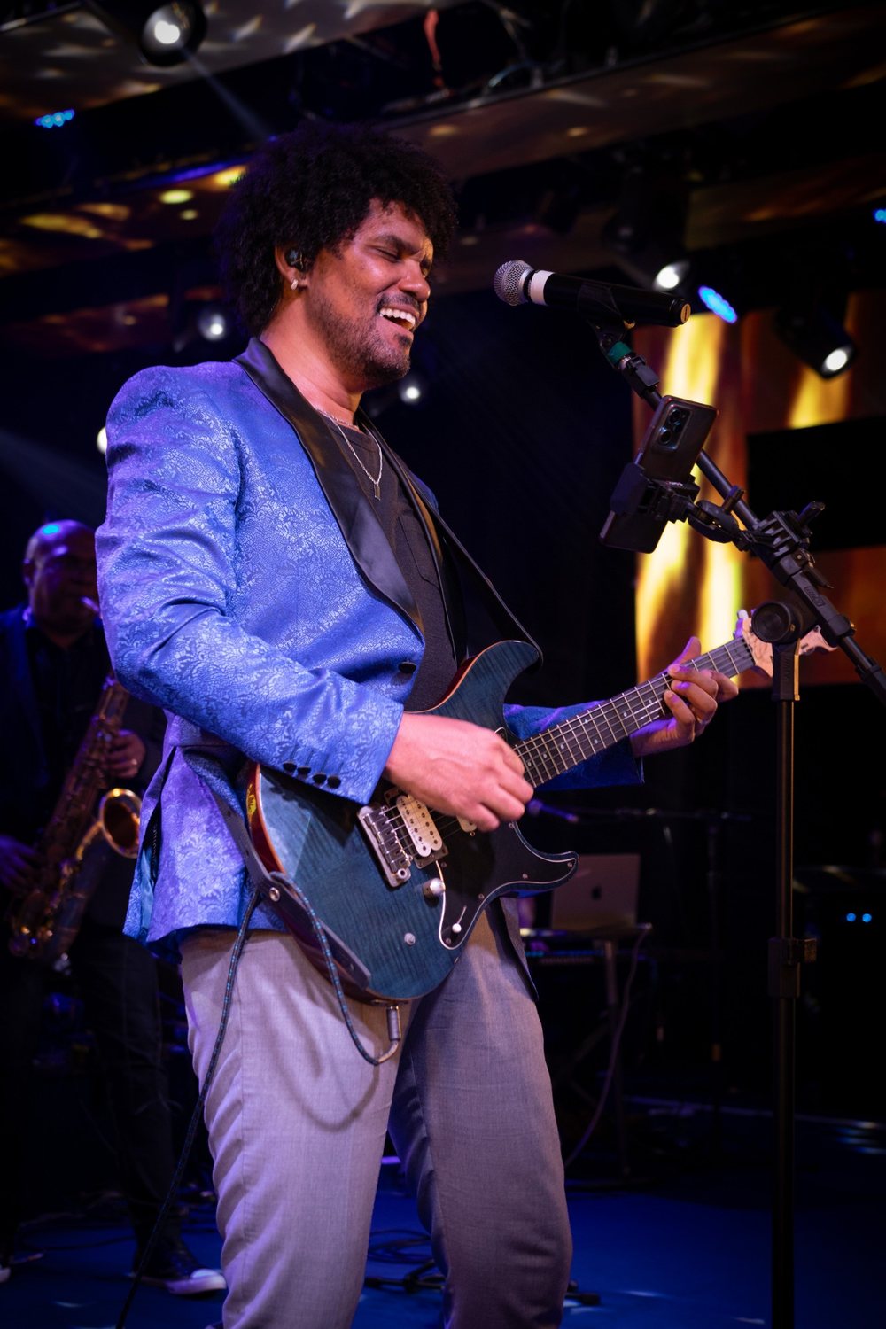 Ivan sorrindo, tocando guitarra no palco